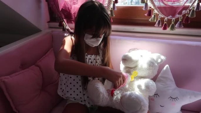 可爱的女孩用洗手液清洁她的泰迪熊防护面具
