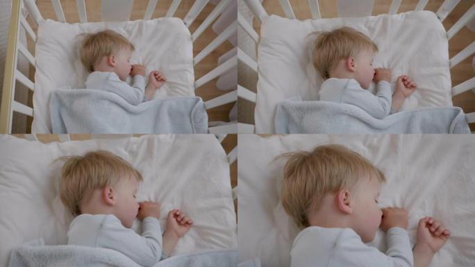 婴儿睡觉，英俊的孩子白天在房间里婴儿床的柔软舒适的枕头上睡得很香