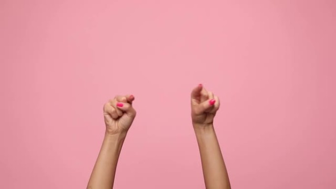 女人在空中牵着手，指着手指，在粉红色的背景上跳舞