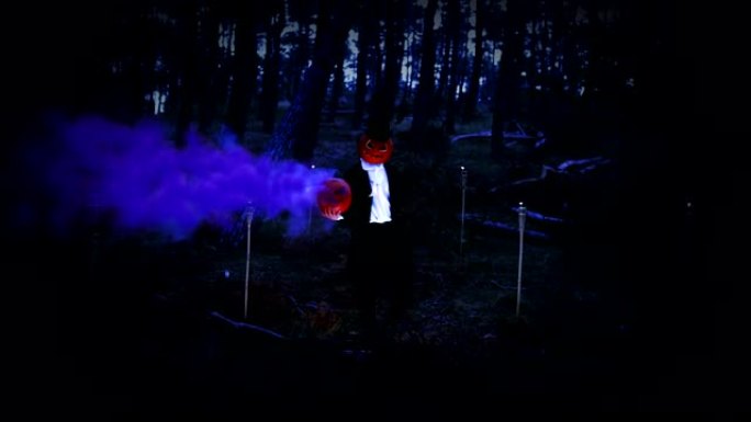 幽灵般的南瓜头男人在森林里拿着一个蓝色烟雾的大南瓜