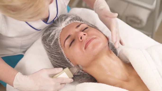 超声波剥离。皮肤科医生对女性客户进行超声波空化面部去皮和清洁。超声波皮肤治疗