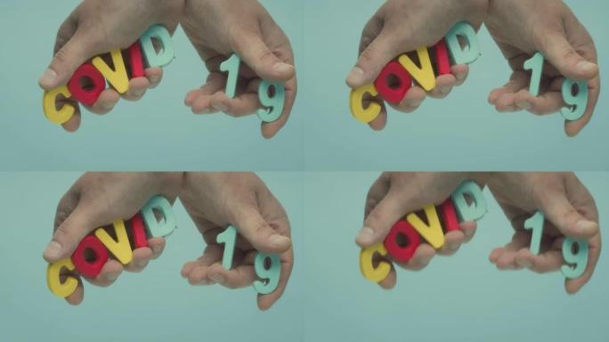 两只手握着用塑料字母制成的单词 “COVID 19”。
