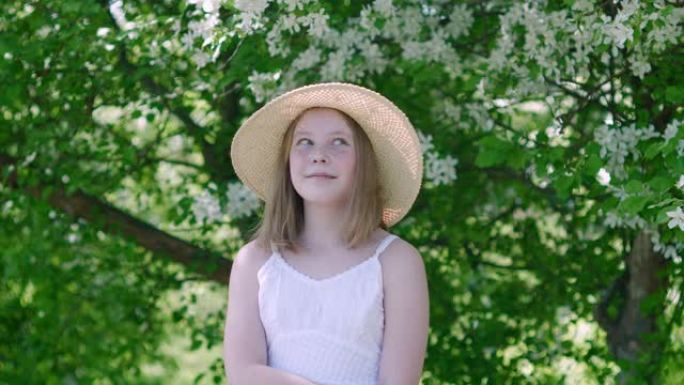 美丽微笑的年轻女孩在盛开的花园里旁观