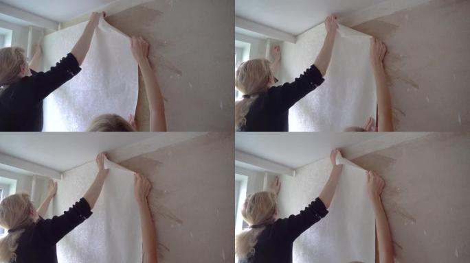 两个女人在家里的一个房间里把墙纸贴在墙上。