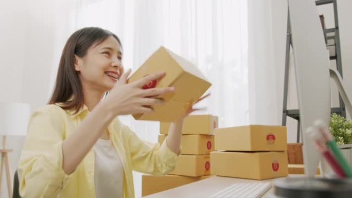 年轻的亚洲女性展示盒包装产品并发送给客户。
