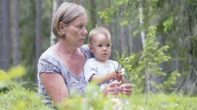 一岁的小女孩了解世界。一岁时与祖母在森林背景下的小女孩肖像