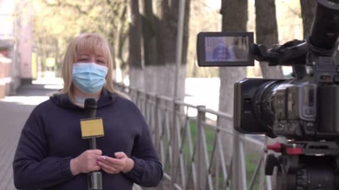 一名戴着防护医用口罩的女记者正在一个荒芜的城市报道。
