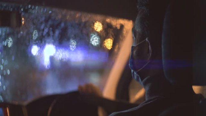 戴医用口罩的年轻人在下雨的傍晚坐在车里