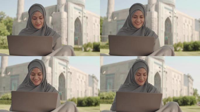 清真寺附近使用笔记本电脑的女人