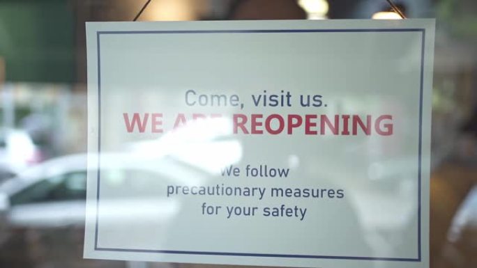 新型冠状病毒肺炎大流行期间咖啡店重新开业的信息标志挂在玻璃门上