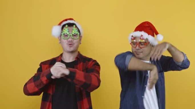 两个亚洲男人正在庆祝新年和圣诞节。当他们戴着眼镜时，他们欢欢喜喜地跳舞。4k分辨率。
