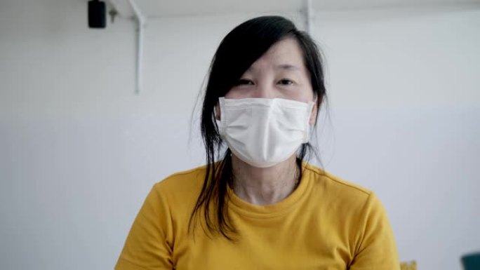在家工作时戴着面具微笑的亚洲女人的概念。