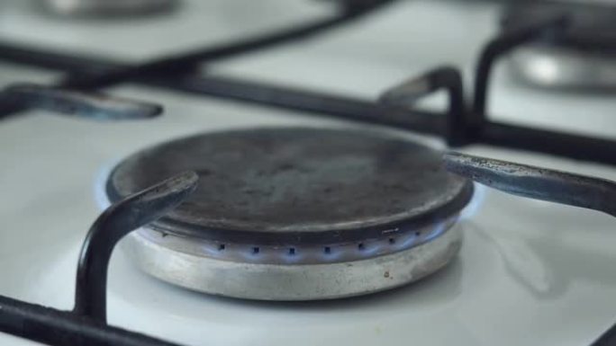 燃气燃烧器在厨房炉灶上用蓝色火焰燃烧。天然气在日常家庭生活中的使用。打开和关闭燃气燃烧器。