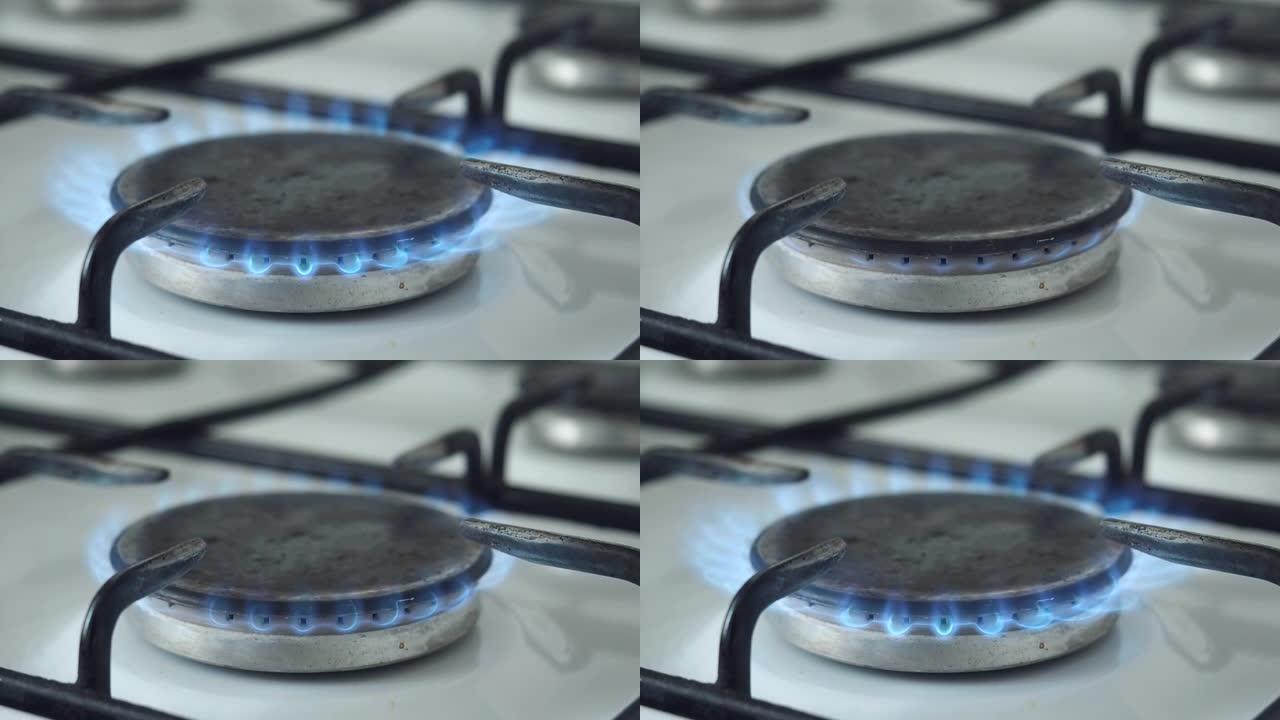 燃气燃烧器在厨房炉灶上用蓝色火焰燃烧。天然气在日常家庭生活中的使用。打开和关闭燃气燃烧器。