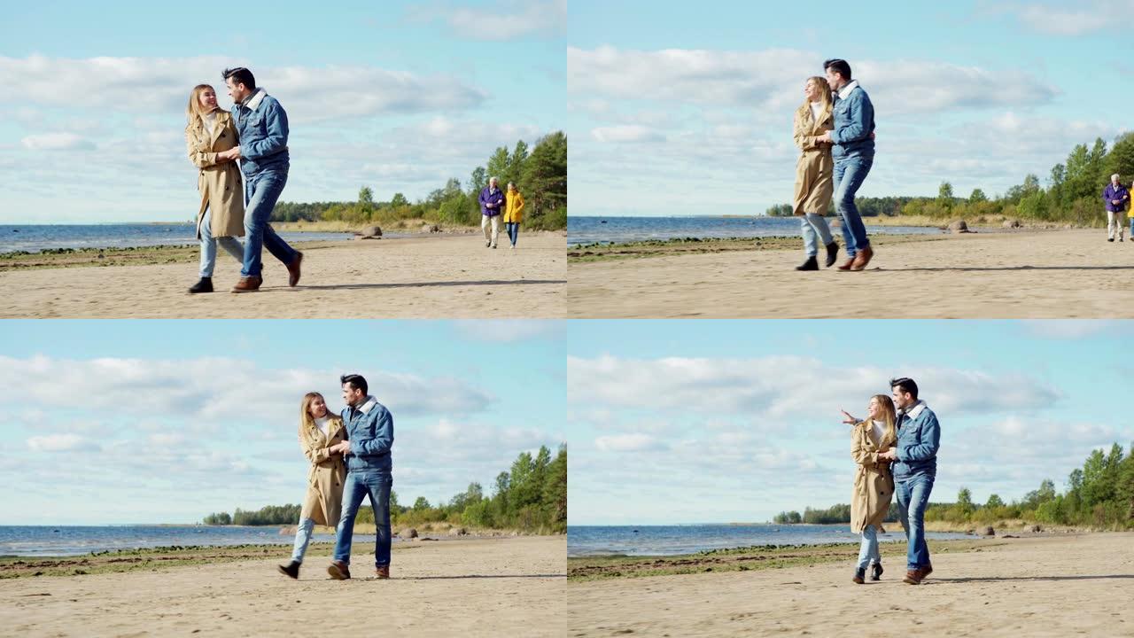 充满爱心的年轻夫妇拥抱在海边散步，欣赏风景秀丽的海景，感到幸福。浪漫的高级恋人手挽手走在他们身后