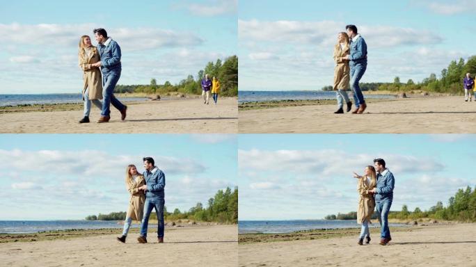 充满爱心的年轻夫妇拥抱在海边散步，欣赏风景秀丽的海景，感到幸福。浪漫的高级恋人手挽手走在他们身后