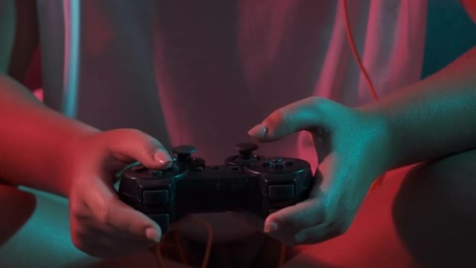 玩的时候用游戏机控制器特写女人的手。五颜六色的灯光