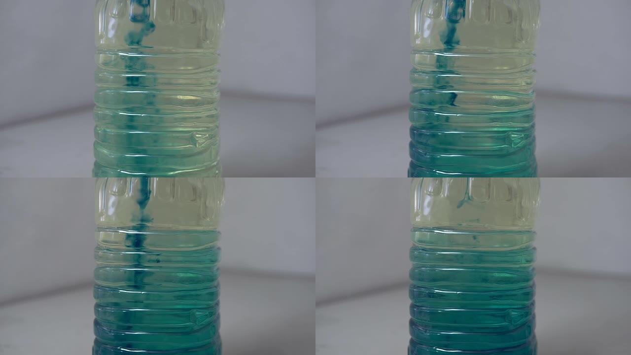 在透明塑料瓶中将蓝色油与汽油混合