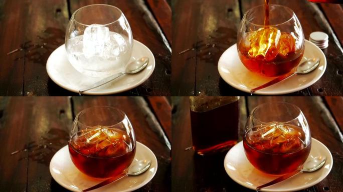 从上方放在木桌上的玻璃杯中，将冰块放在瓶中，将咖啡冷煮。一瓶冷冲泡咖啡和冰杯，准备冷冲泡饮料。男子将