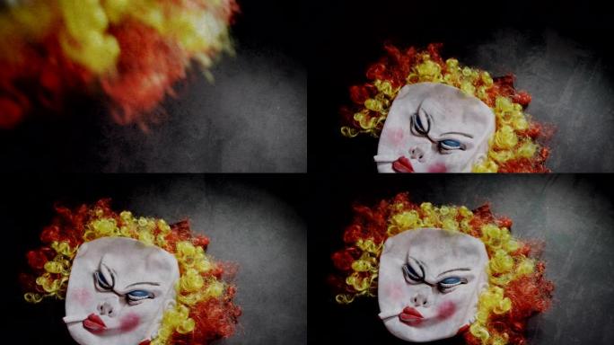 恐怖的小丑面具在闪烁的背景下掉落在灰色表面上