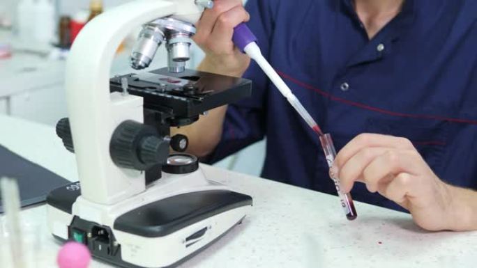 科学家准备血液样本用于显微镜研究。将血样放在显微镜上幻灯片专家准备用于显微镜研究的血样。将血样放在显