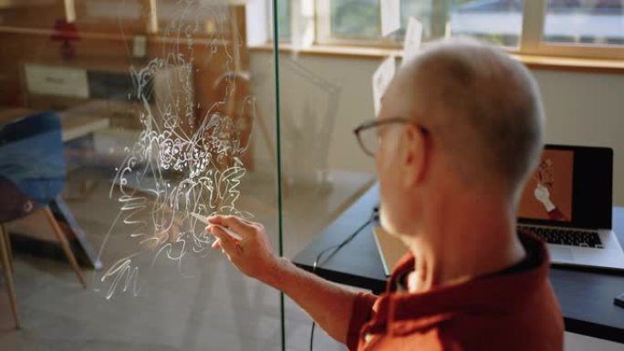 高级艺术家在他的家庭办公室的玻璃墙上绘画