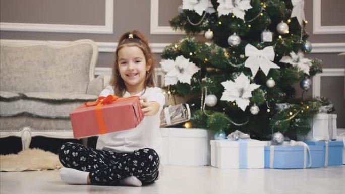 广告视频，小女孩得到了一个礼品盒，并在圣诞节背景下将其呈现在镜头前。