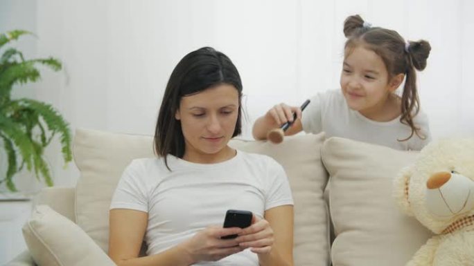 小女孩和妈妈坐在沙发上玩耍的4k慢动作视频。