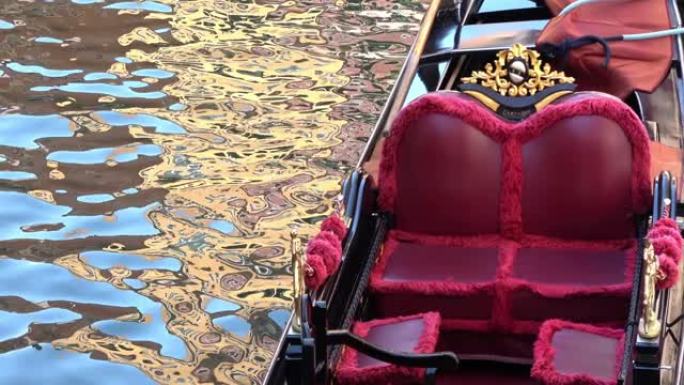 4K.贡多拉停在意大利威尼斯的一条运河上。带金色装饰品的红色座椅