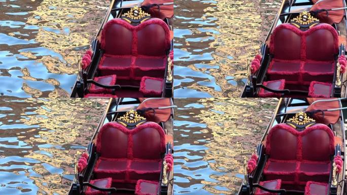 4K.贡多拉停在意大利威尼斯的一条运河上。带金色装饰品的红色座椅
