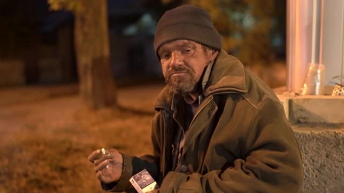 无家可归的人在秋天的夜晚在街上吃饭。