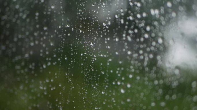 强烈的雨水冲向窗户玻璃并流下来。特写。雨季玻璃背景上的雨滴