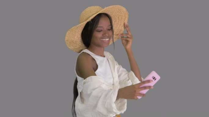 微笑的非洲裔美国妇女戴着草帽边走边自拍，阿尔法频道
