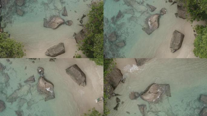 无人机在印度洋海岸附近的一块岩石上缓慢地旋转着一个身材苗条的美丽女孩。