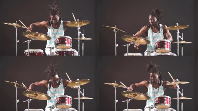 漂亮的带有辫子的非洲艺术鼓手坐在用棍子敲打的鼓上