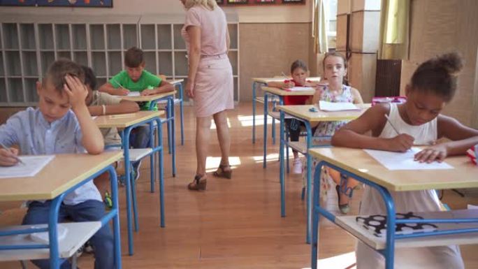 女小学教师观察她的学生在做教育考试