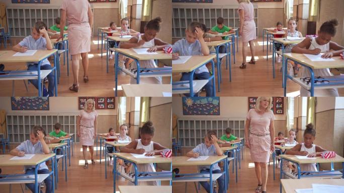 女小学教师观察她的学生在做教育考试