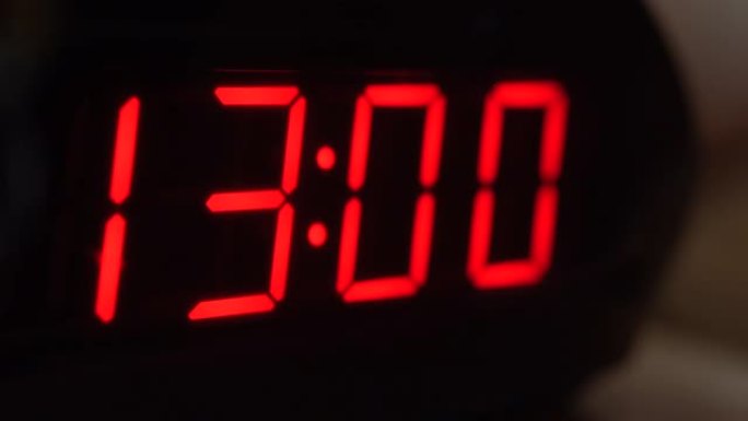 黑色数字时钟屏幕的特写显示13.00。黑色背景上闪烁红色数字。现代定时器系统和霓虹灯、电动报警装置