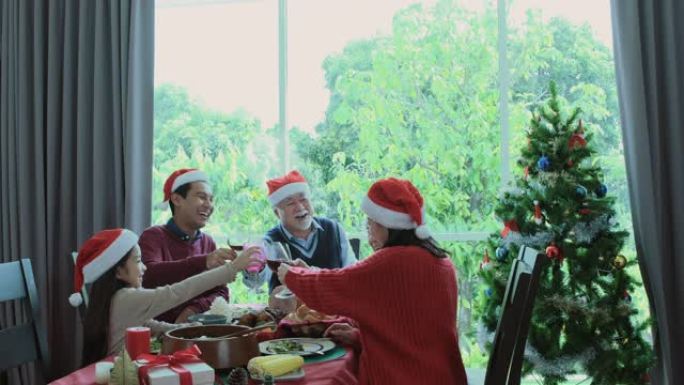 干杯，老人戴着红帽子，在圣诞节与家人共进晚餐