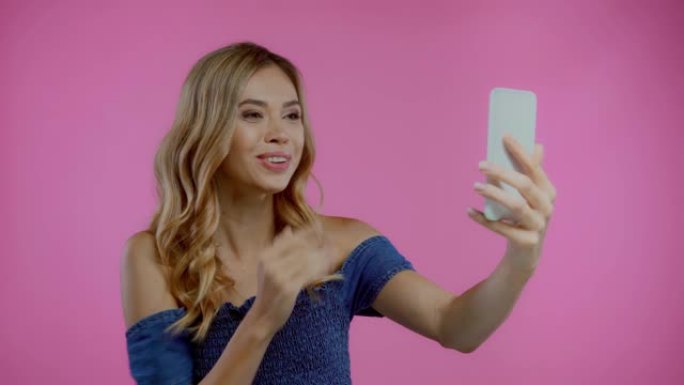 金发女人在紫色的智能手机上进行视频通话时打手势