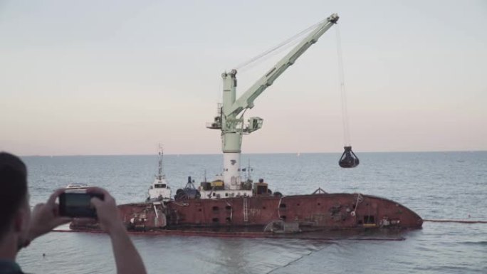 男性博客作者正在敖德萨附近沉没的油轮德尔菲附近的社交网络上直播。黑海海岸。男子使用智能手机摄像头创建