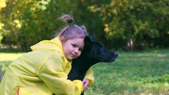 特写黄雨中的女孩拥抱一只黑狗