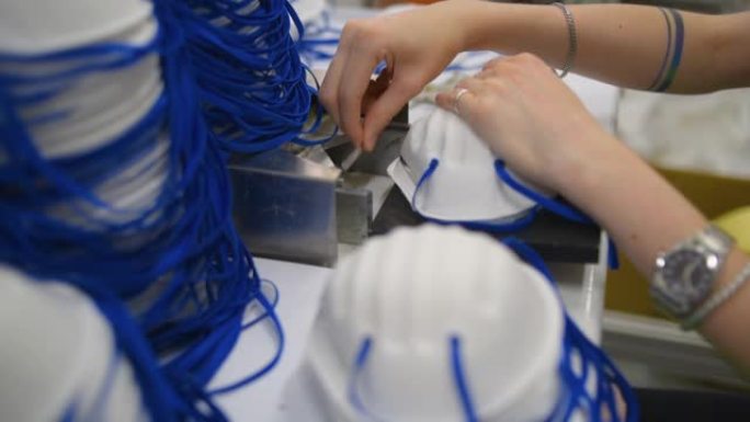 一名妇女在一家工厂工作，生产带有纳米纤维的医用口罩，并在机器上使用超声波焊接环。冠状病毒和新型冠状病
