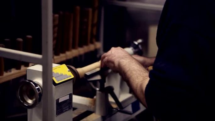 木匠男手用凿子在机器上从木片上切割木制旋钮，加工形式，装饰。慢动作。侧视图