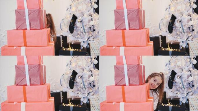 可爱的孩子为她的朋友和家人准备了圣诞礼物，并从一堆红色礼品盒后面偷看。