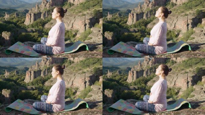 Vlogging教程。年轻的孕妇在户外做放松瑜伽练习，身后有雄伟的风景背景。展示如何在怀孕期间锻炼。