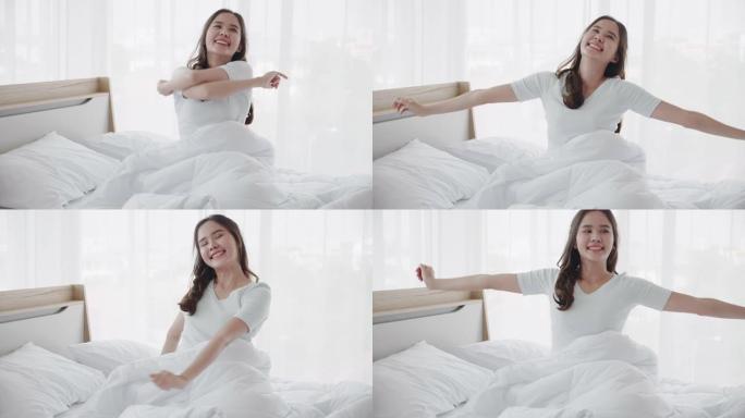 美丽的亚洲女人早上醒来感到精神焕发和快乐。充足的睡眠有助于保持你的健康。清洁卧室没有细菌和疾病。概念