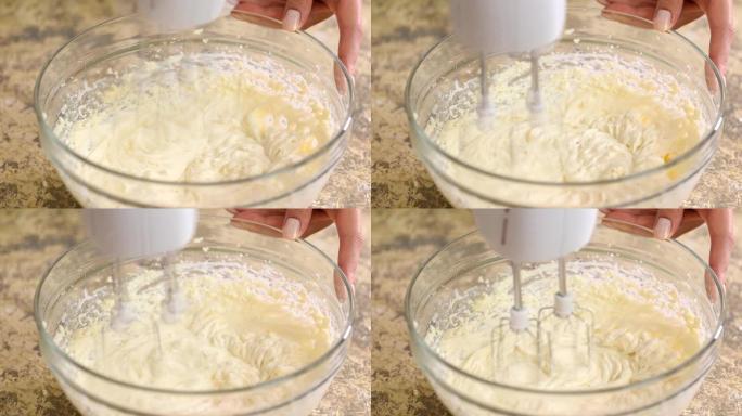 用搅拌器混合蛋糕的奶油。特写。