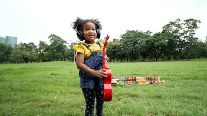 混血女孩在绿草和花周末假期的公园里有趣地玩耍。慢动作镜头。吃红苹果。
