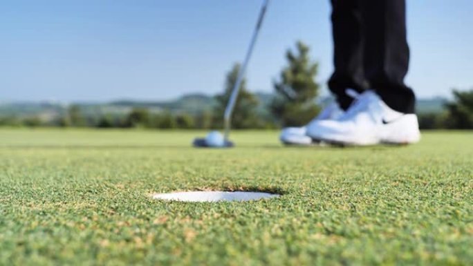 高尔夫球手把球推洞在绿色高尔夫球场，天空的场景背景。